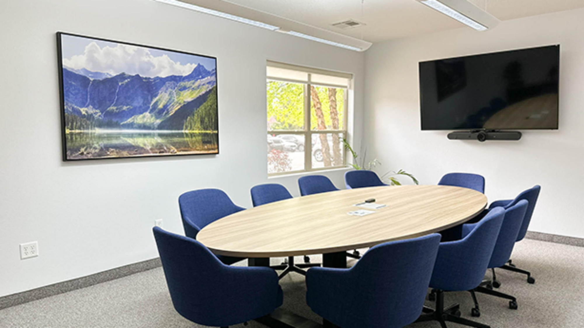 Corporate conference room featuring large meeting table and integrated video conferencing display