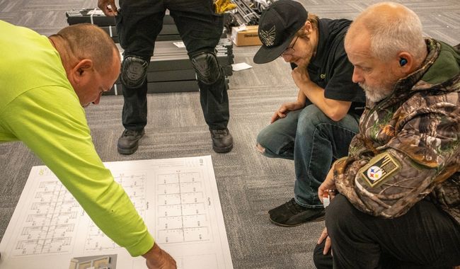 Create Spaces installation team reviewing a project floor plan on-site